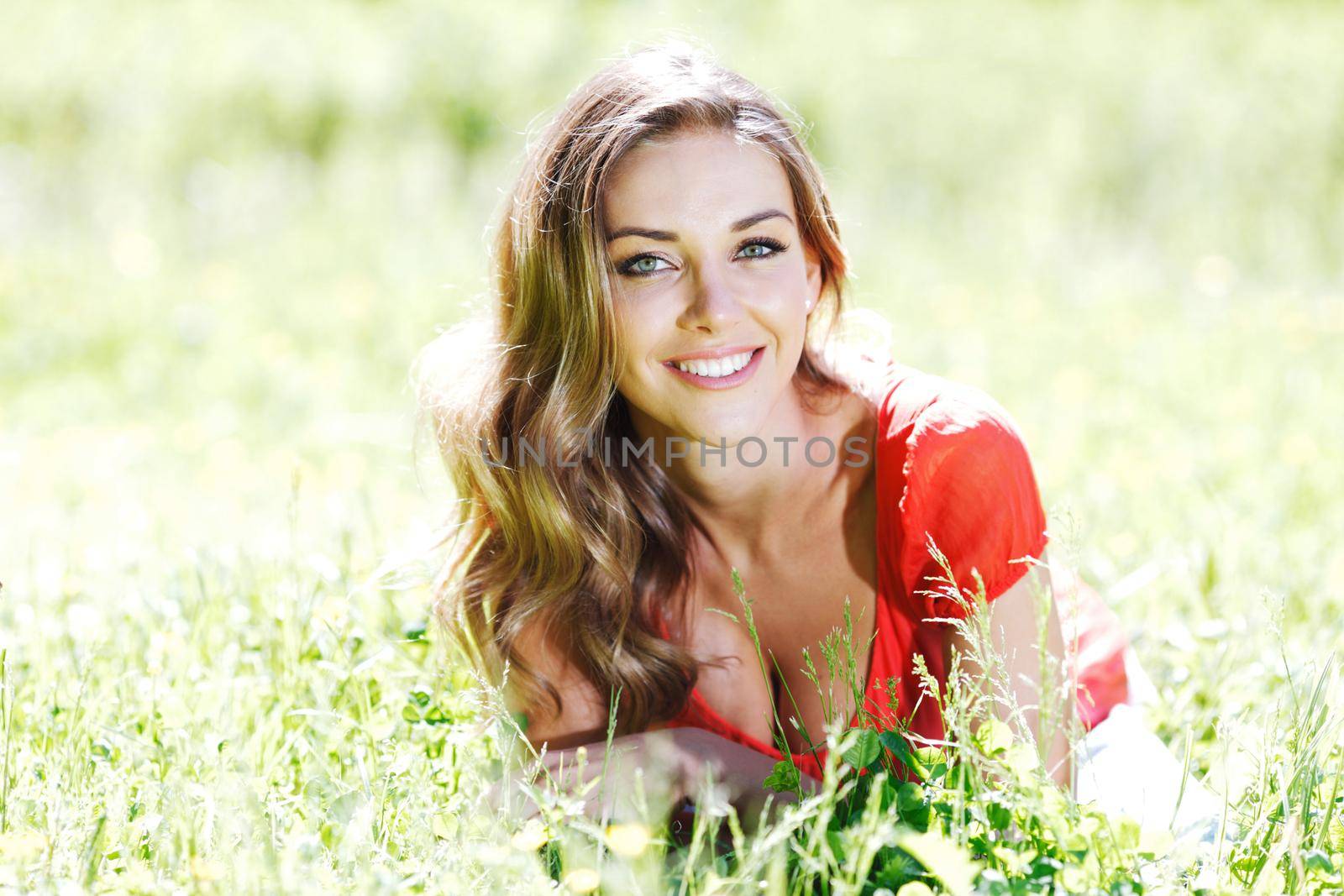 Beautiful healthy Young Woman relaxing on the green grass and smiling