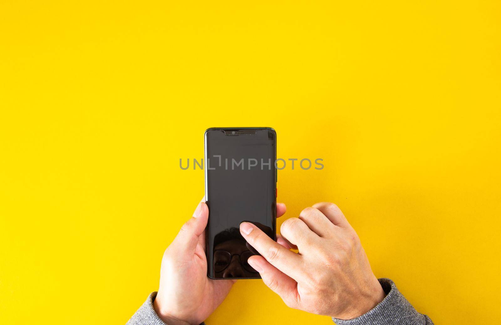 Top view of male hand holding smartphone with yellow color background with copy space. by tehcheesiong