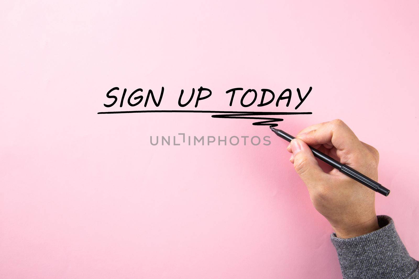 A hand writing a word SIGN UP TODAY on pink background by tehcheesiong