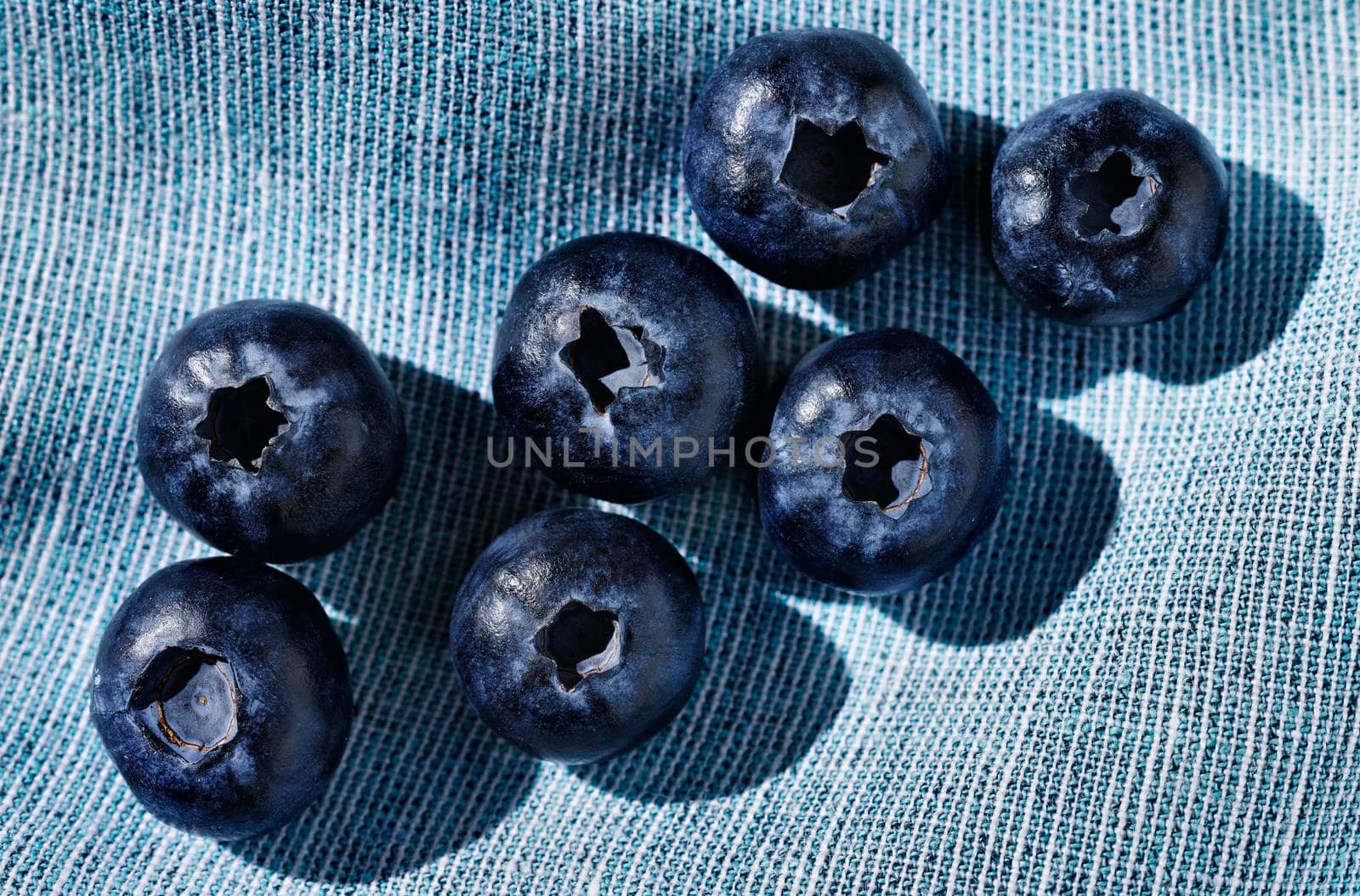 Fresh blue bilberries on blue cotton tablecloth ,beautiful round dark fruit