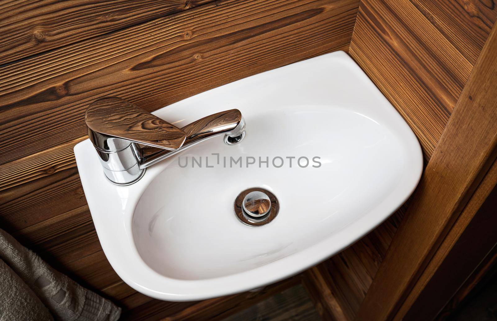 Small white wash basin, wooden walls around, closeup detail.