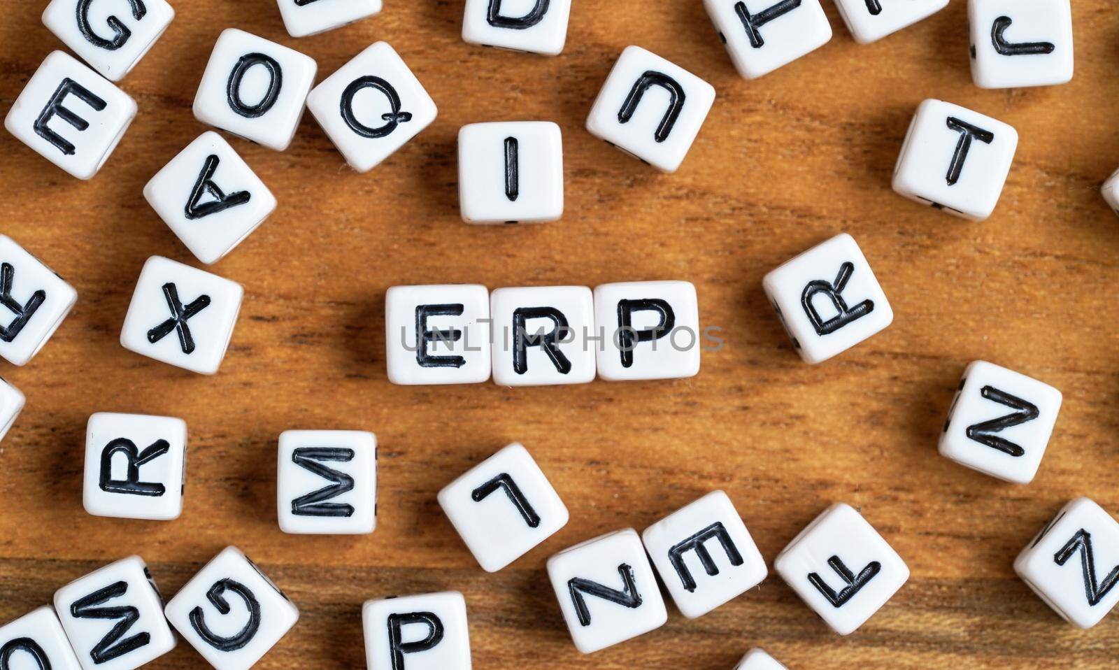 Small white and black bead cubes on wooden board, letters in middle spell ERP - Enterprise resource planning concept.