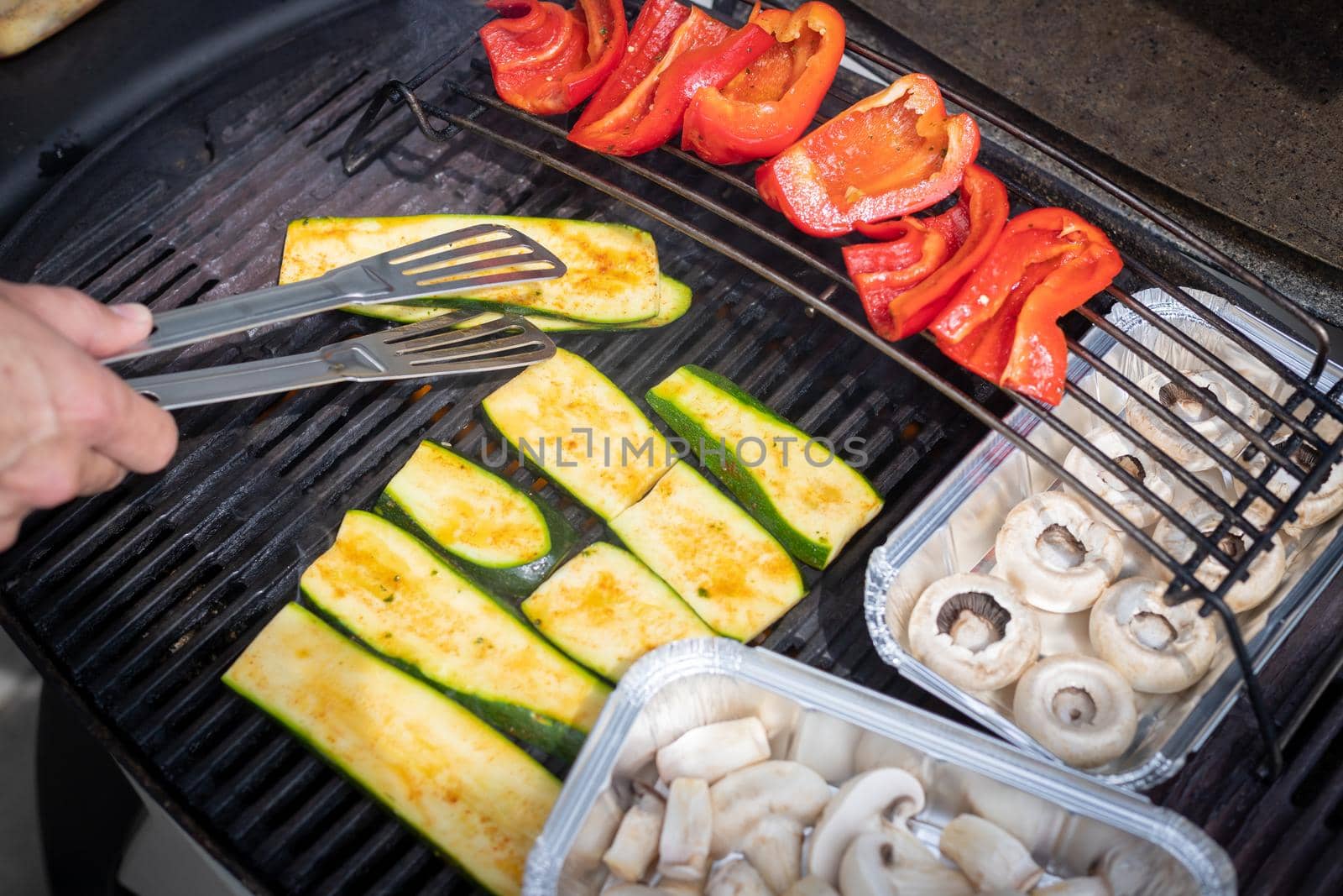 Close up of cheese and vegetables on gas grill. Summer time, outdoors.