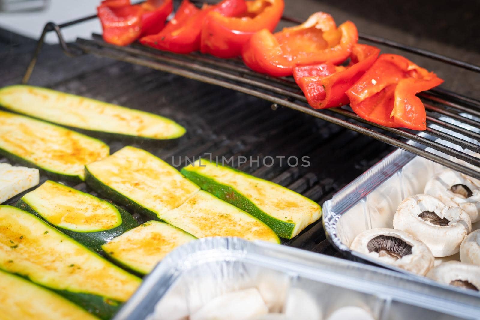 Close up of cheese and vegetables on gas grill. Summer time, outdoors.