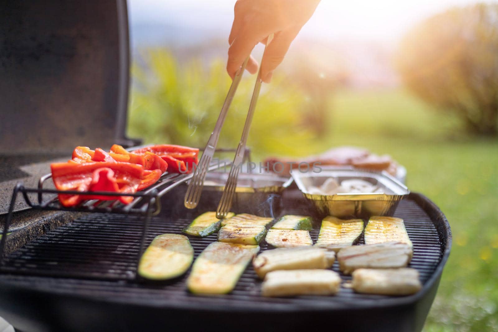Close up of cheese and vegetables on gas grill. Summer time, outdoors.