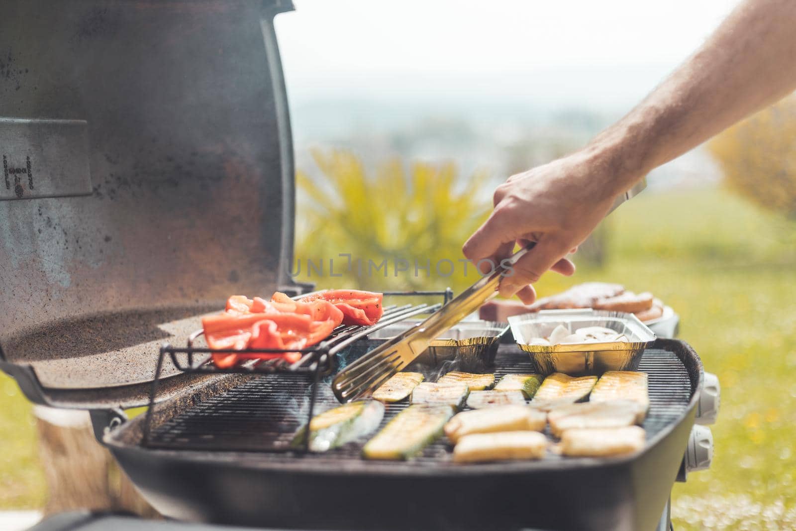 Close up of cheese and vegetables on gas grill. Summer time, outdoors.
