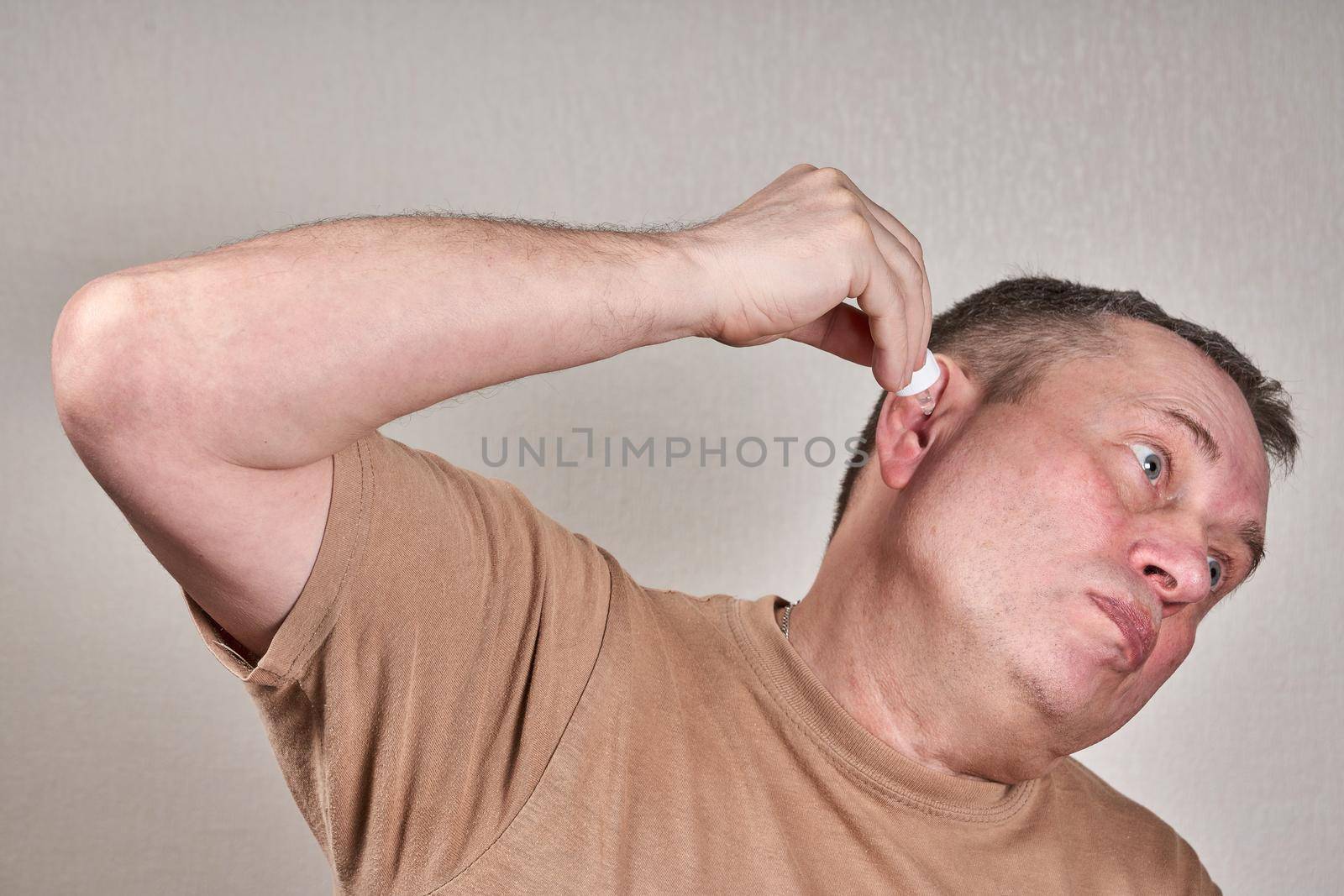 A man instills medicine into his ear with a small pipette from a pharmacy bottle. Self medication at home