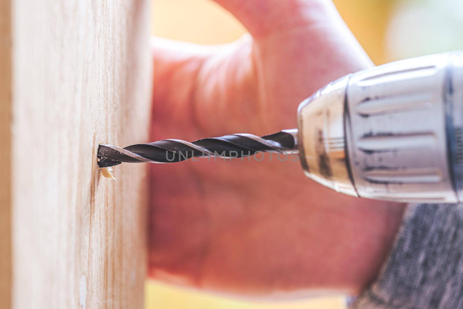 Do it yourself home handyman is using a drill for drilling wood