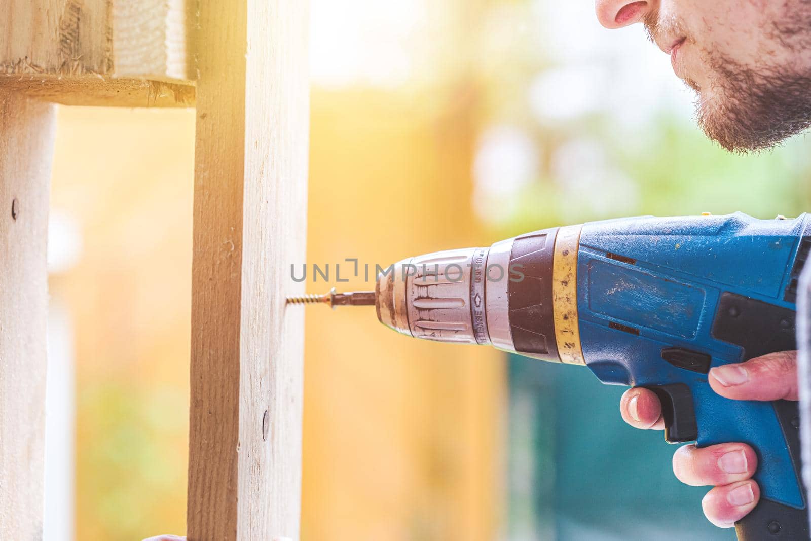 Do it yourself home handyman is using a cordless screwdriver for screwing