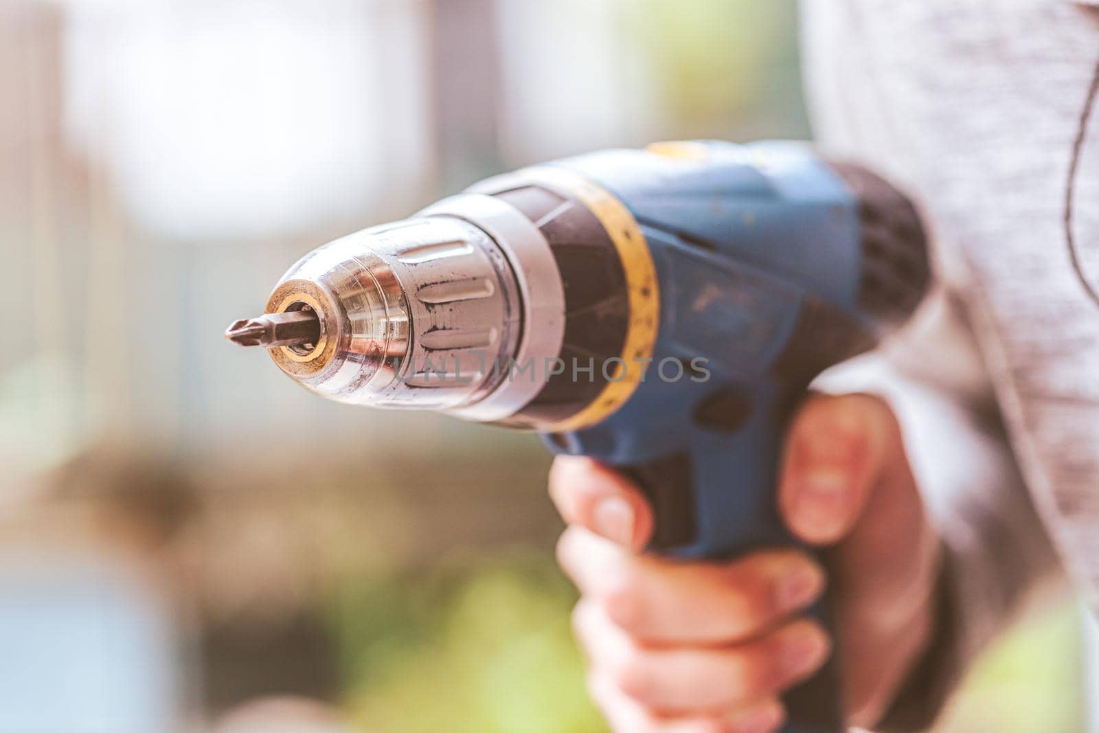 Do it yourself home handyman is holding a cordless screwdriver, outdoors