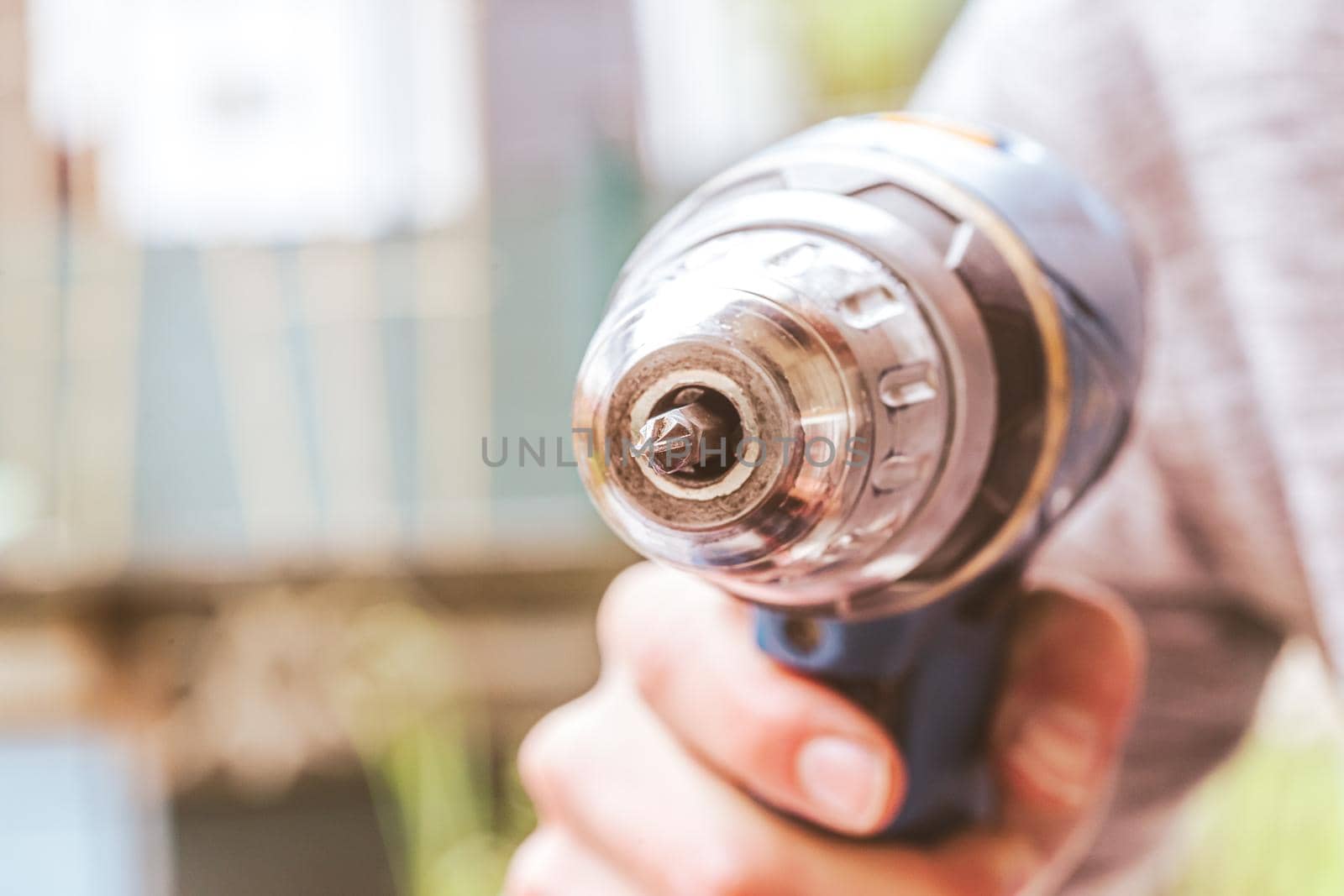 Do it yourself home handyman is holding a cordless screwdriver, outdoors
