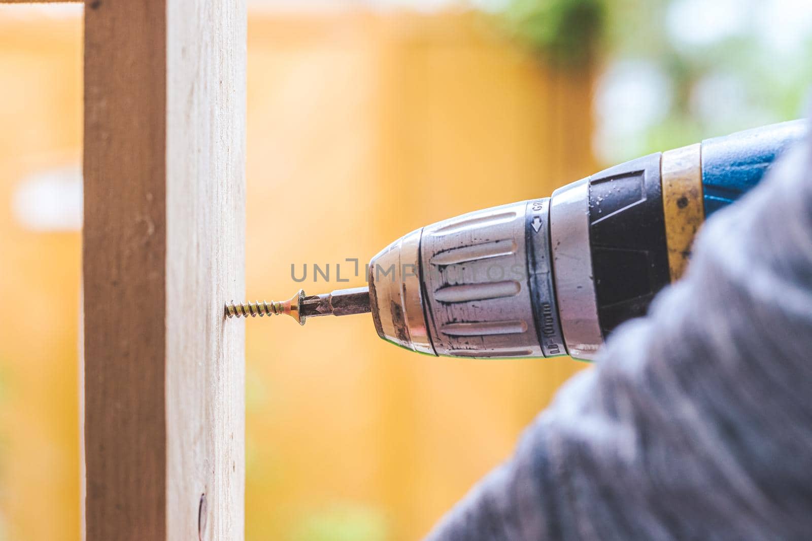 Do it yourself home handyman is using a cordless screwdriver for screwing