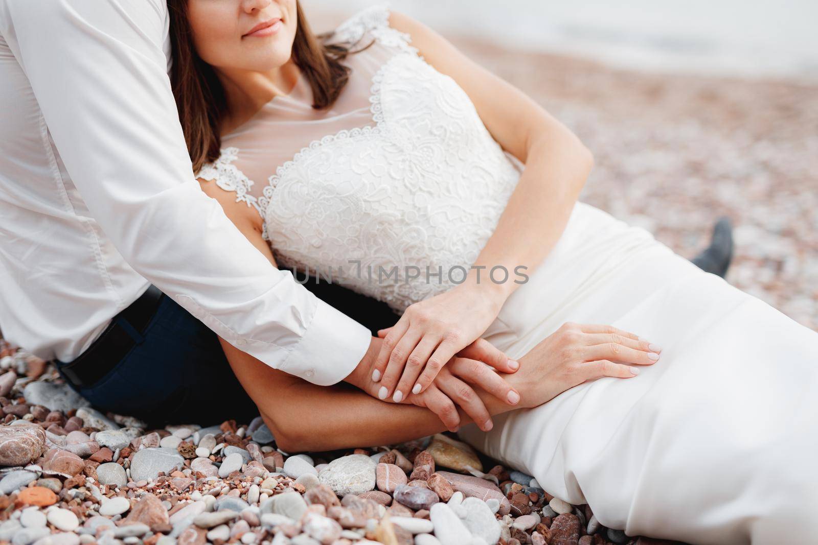Groom in white shirt hugs the bride lying in a white lace dress. High quality photo