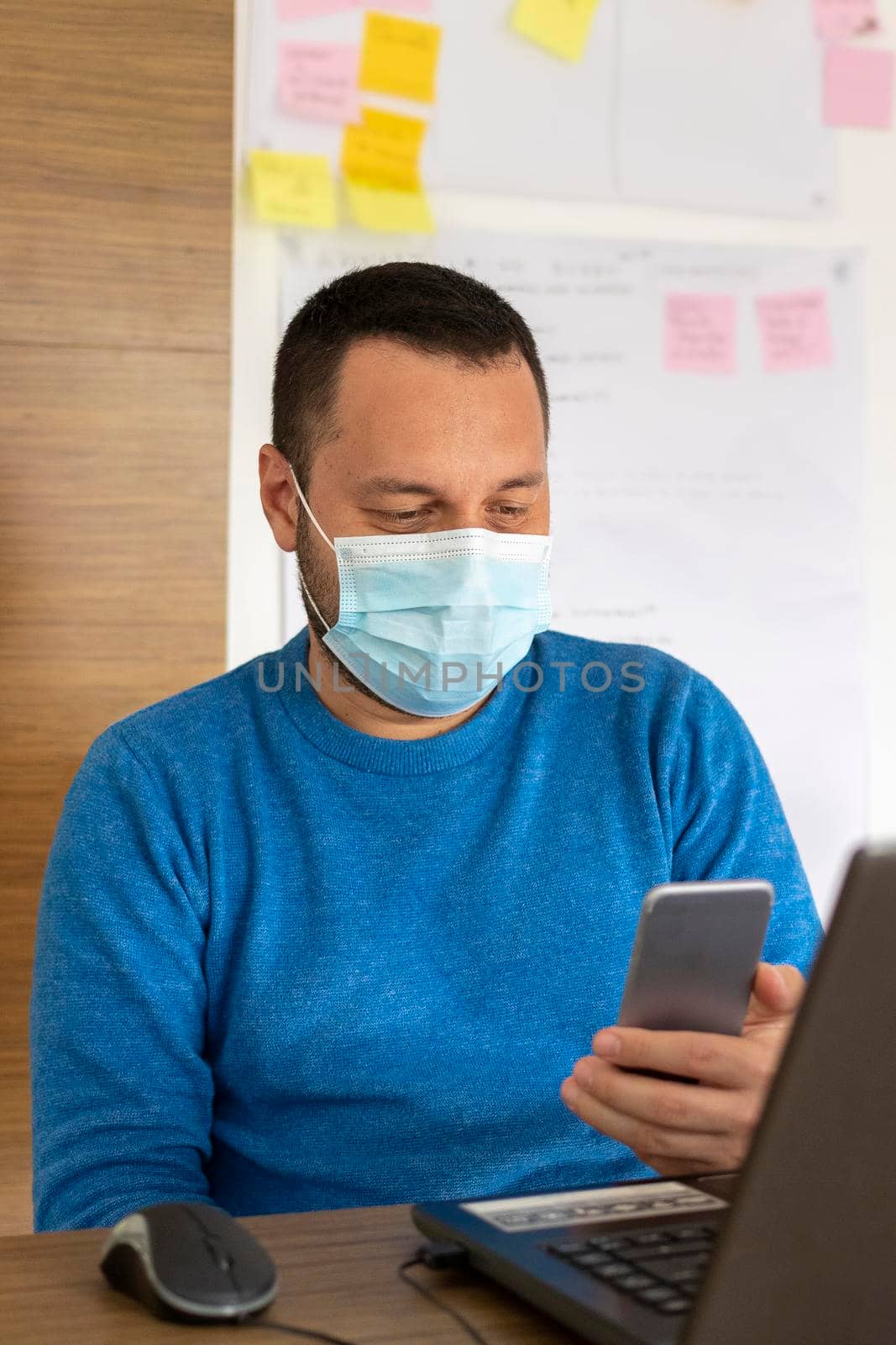 Young man with medical mask working with his laptop