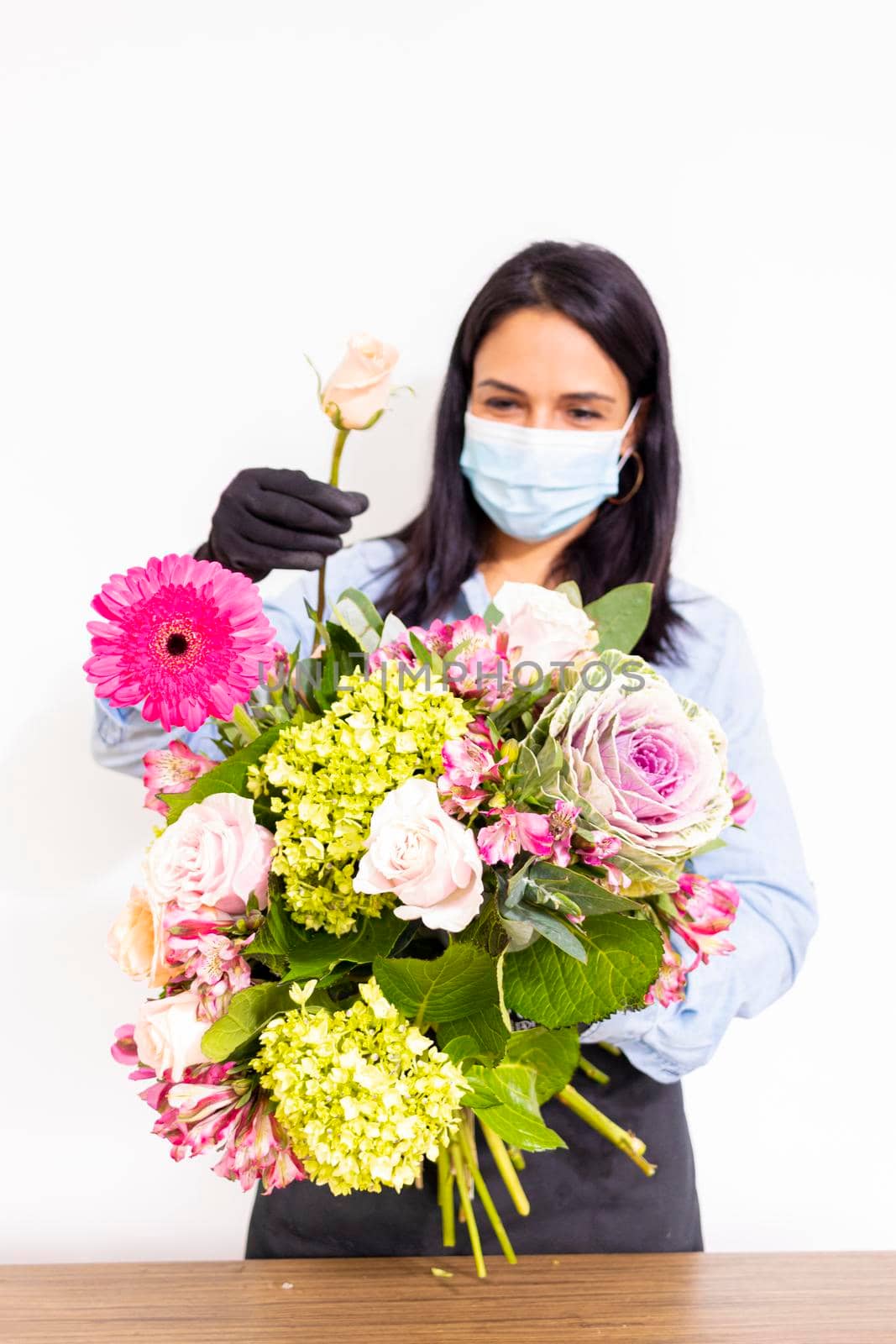 Cute woman florist is making a bouquet of roses, hydrangeas and alstroemerias