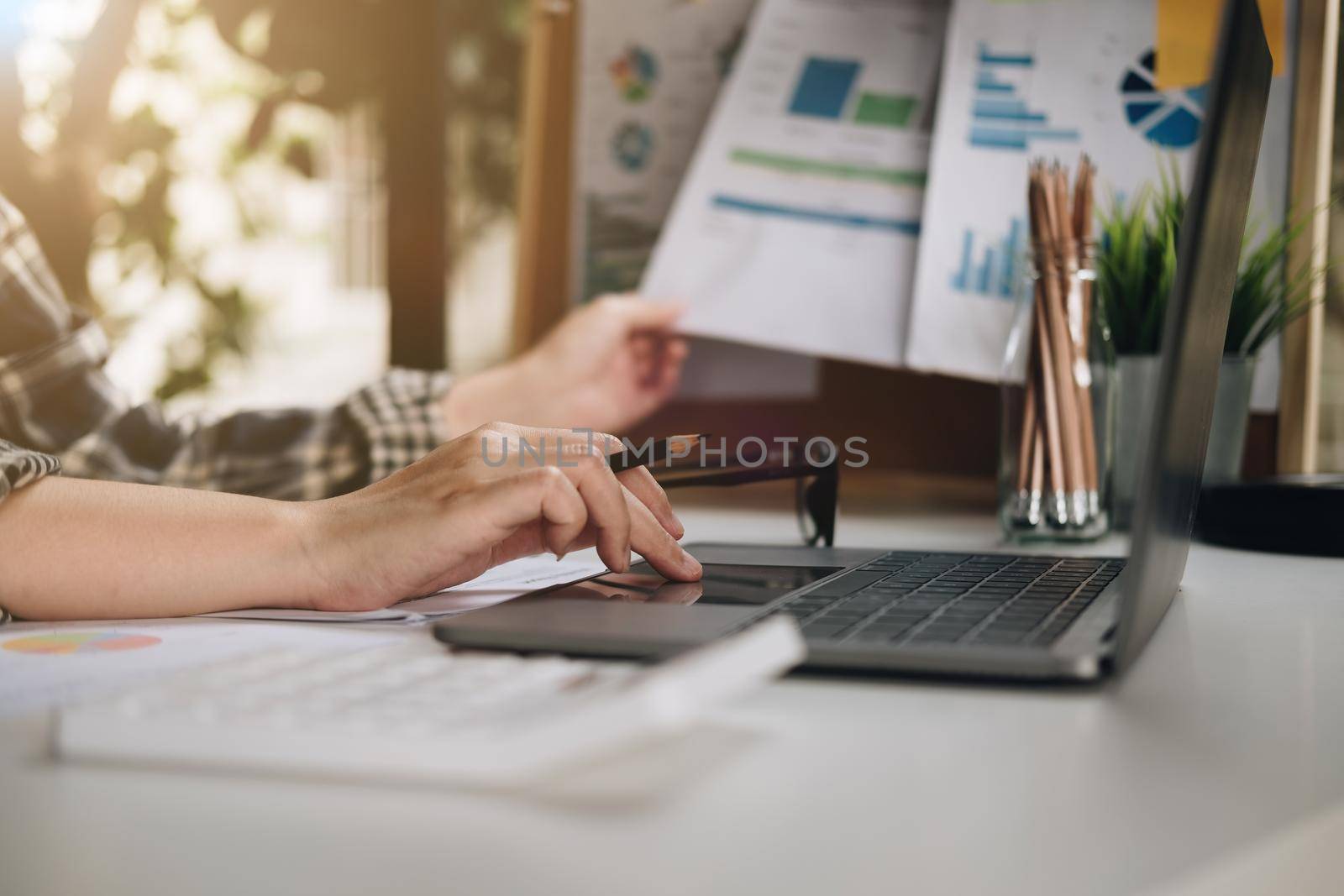 Close up of businessman or accountant hand holding pen working on laptop for business data, accountancy document and laptop computer at office, business concept..