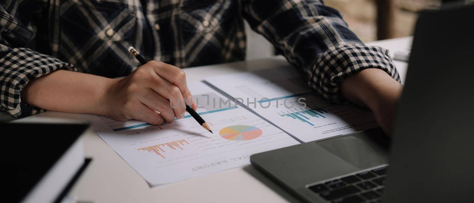 Accountant woman discussing new plan financial graph data on office table with laptop at home by nateemee