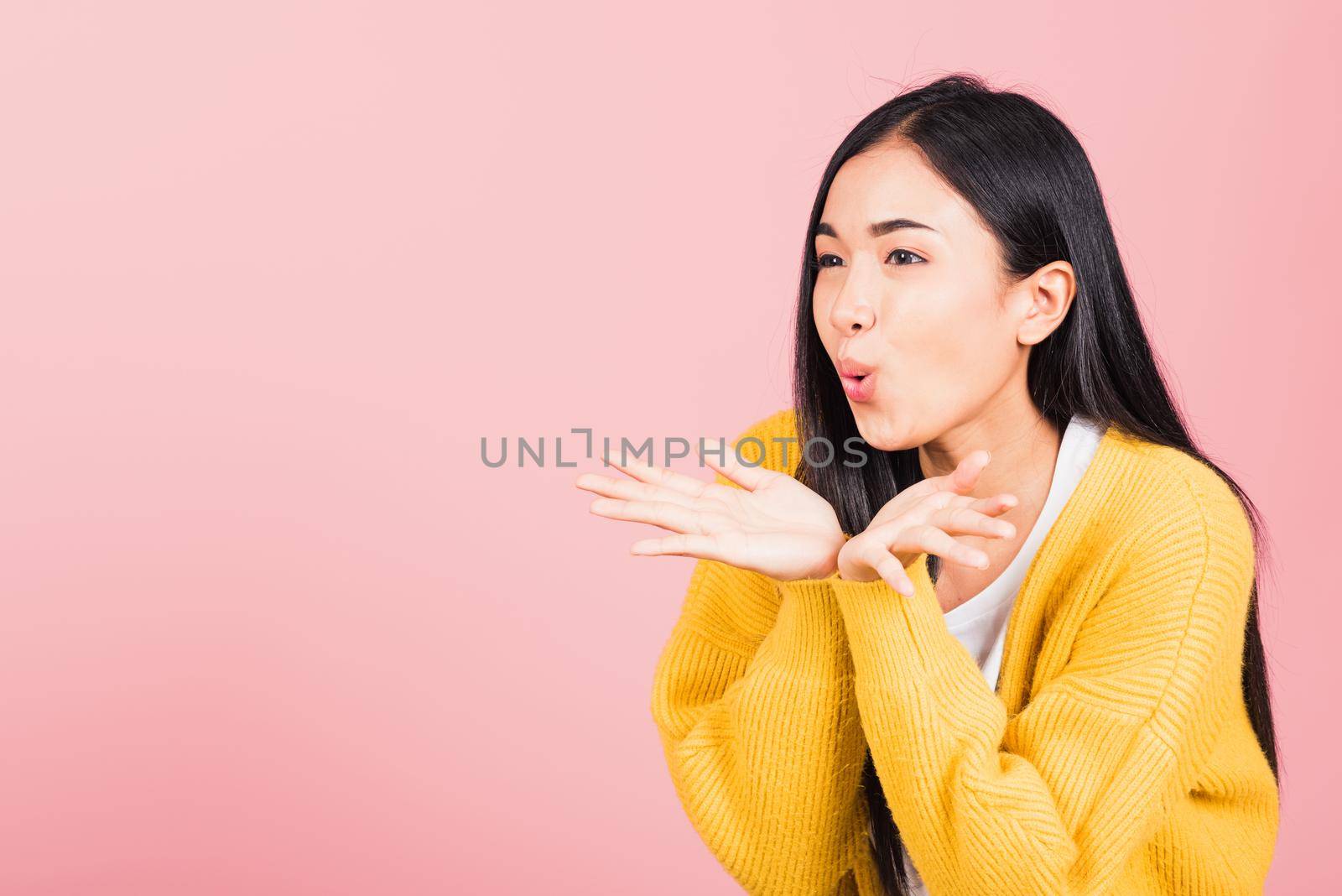 Asian happy portrait beautiful cute young woman teen standing blowing kiss air something on palm hands expresses her love looking to side away studio shot isolated on pink background with copy space