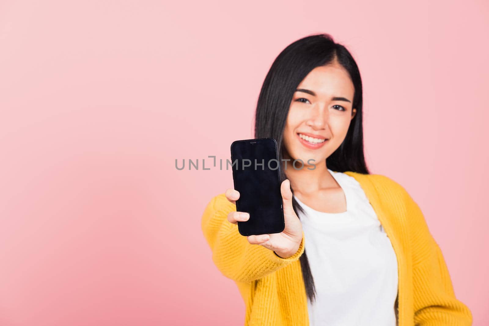 Happy Asian portrait beautiful cute young woman teen smiling excited  holding blank screen mobile phone studio shot isolated on pink background, Thai female show smartphone empty screen space