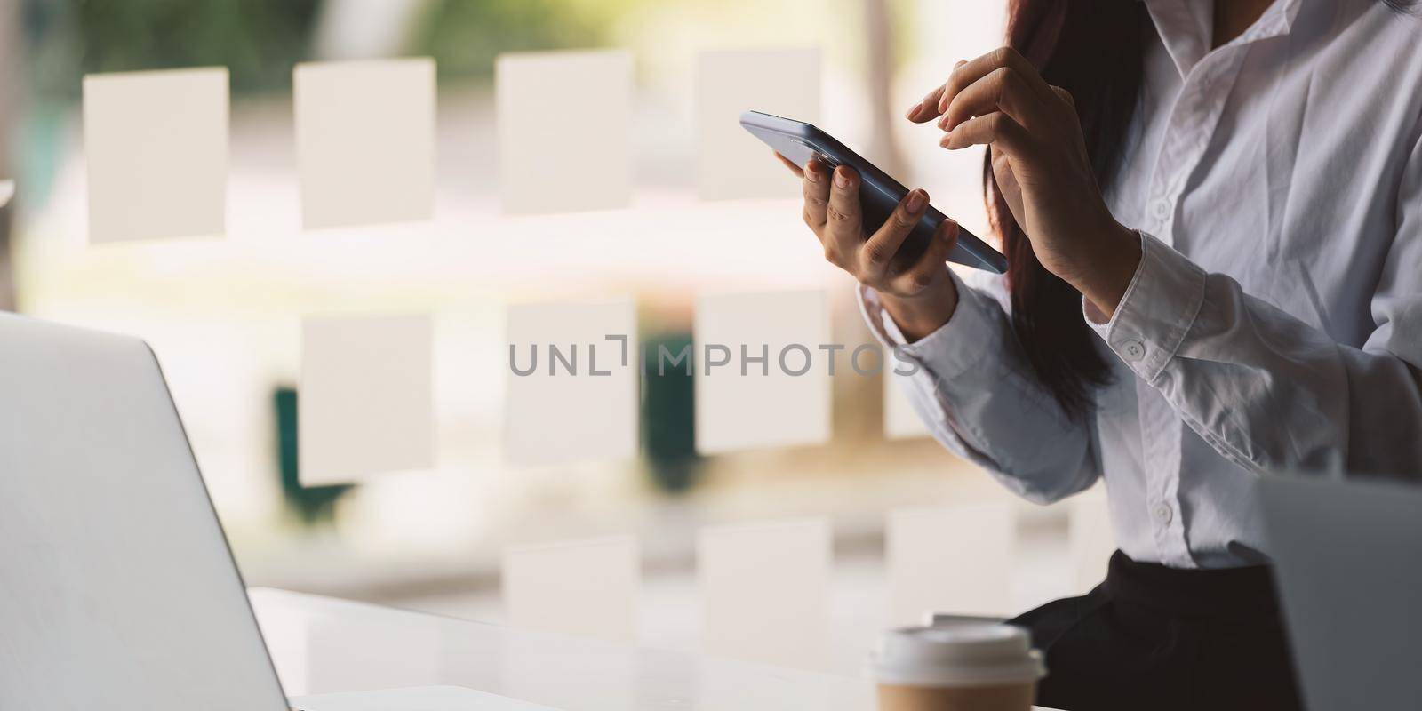 Shot of woman using smart phone at home office.