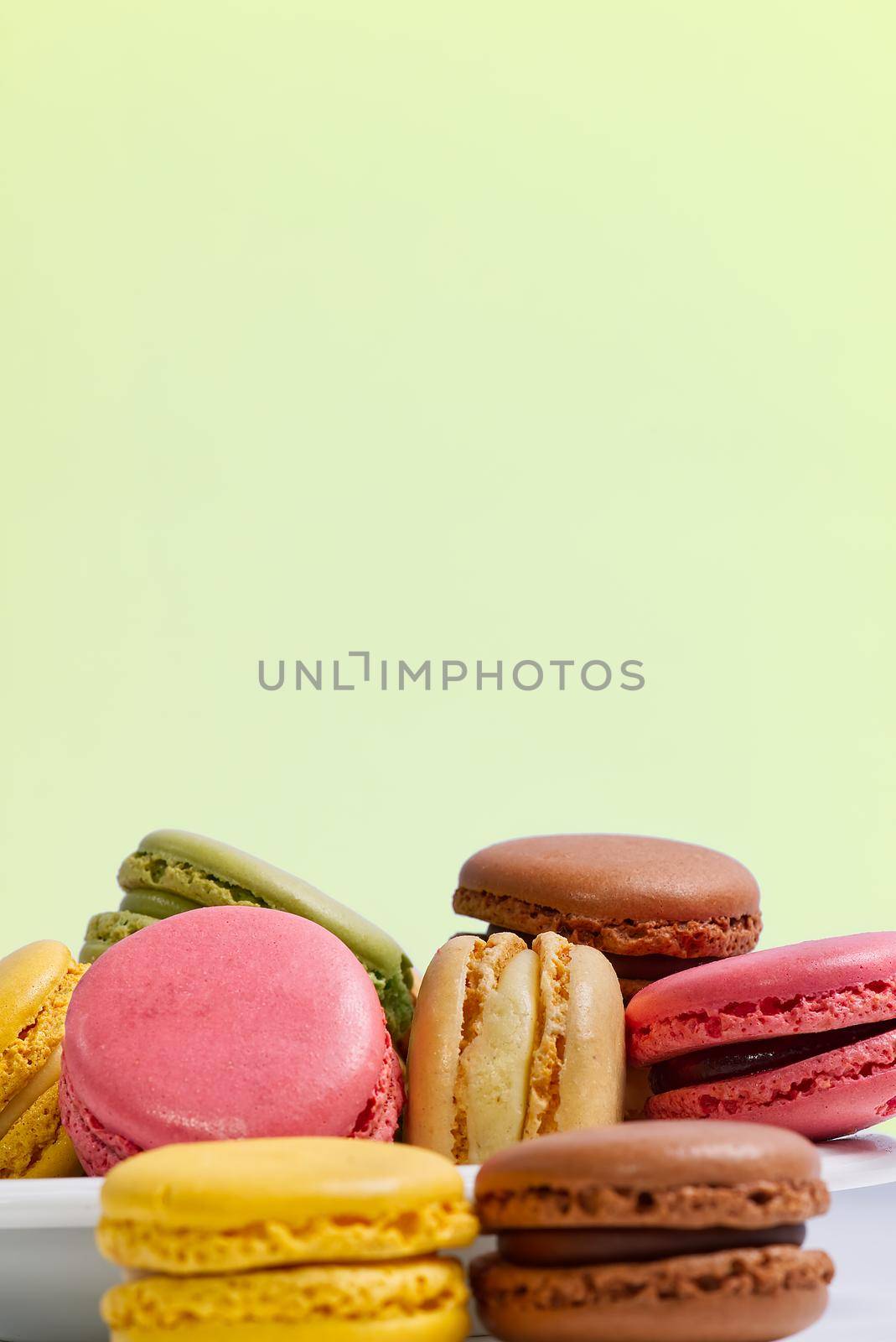 French dessert macaron isolated on green background. Modern Macarons on colorful background. by PhotoTime