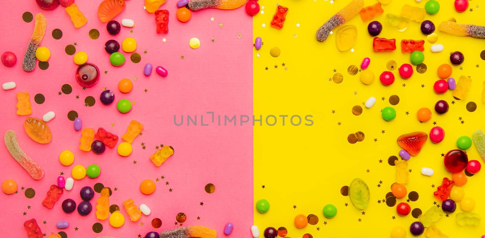 Candy assorted layout. Layout with candy on a yellow-pink background. Chewy marmalade and small caramels . Bright background. Sweets for every taste. An article about sweets. Copy spase