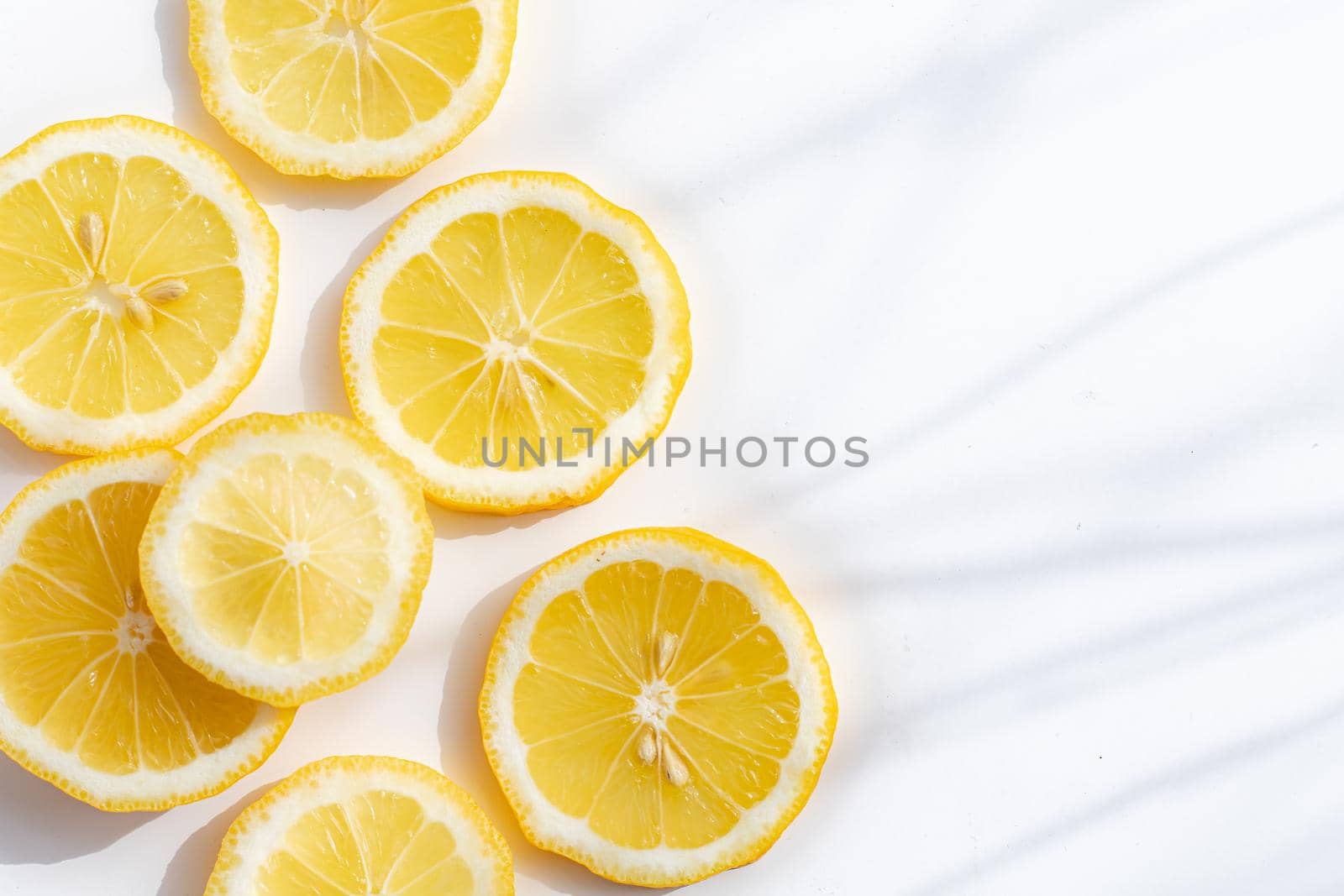 Sliced lemon on a white background . Lemon layout. Sliced fruit. Yellow color. White background. Light and shadow. Citrus. Healthy food. Copy space