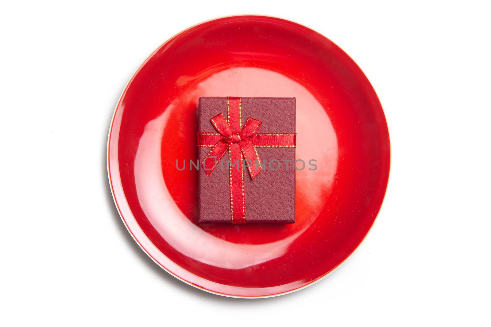 Red gift on a plate . Serving a festive table. New Year and Christmas. Gift wrapping . copy space