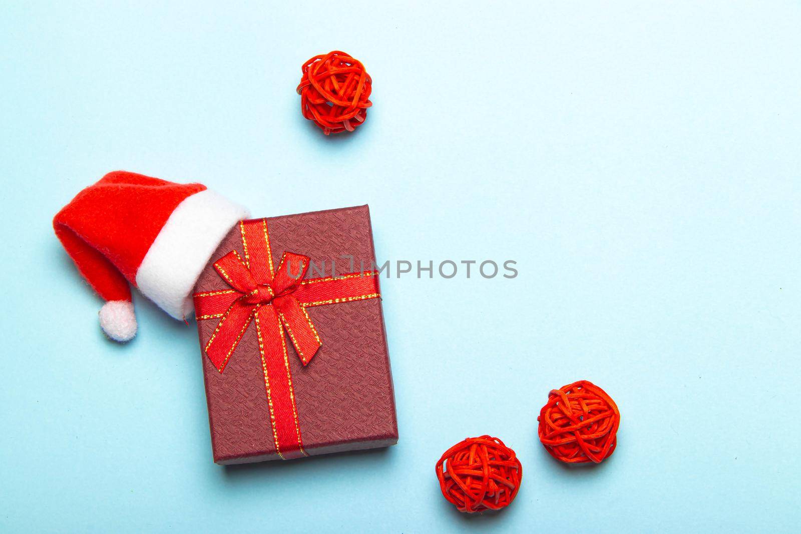 Red gift on a blue background . A gift with a Santa hat. Christmas and new year. A gift for the holiday. Red gift wrap.