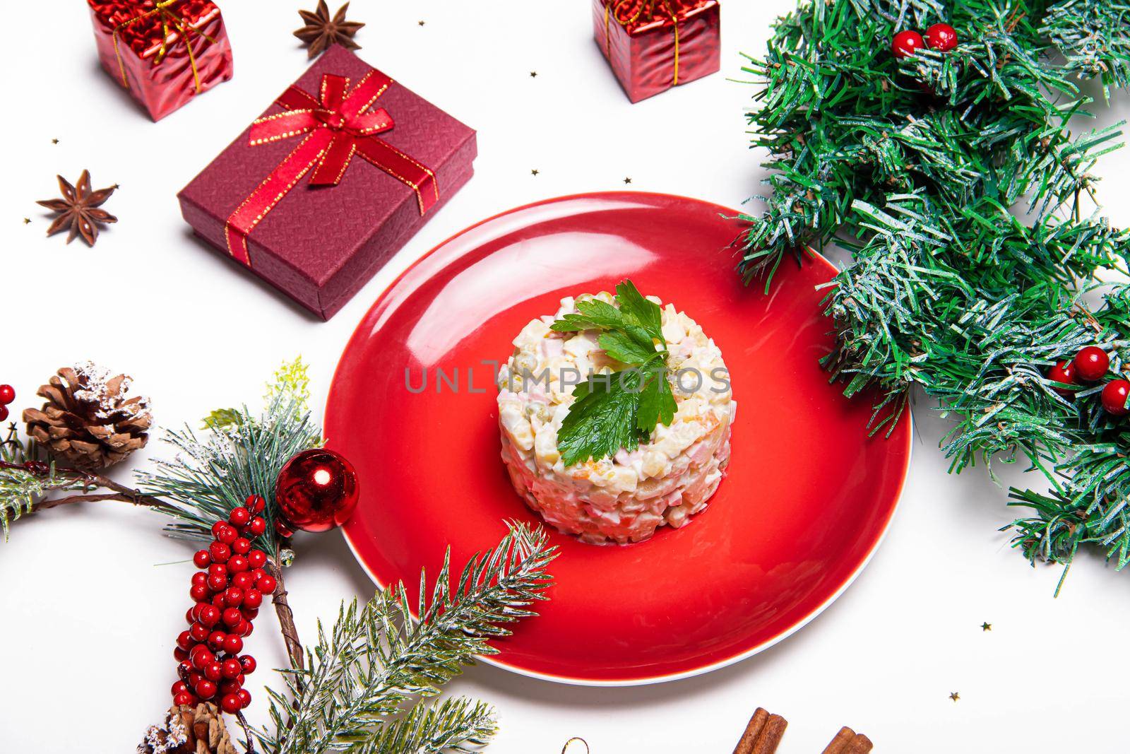 Olivier salad on a red plate . Olivier Christmas . Christmas layout with salad. New Year. Holiday. Festive dish. Table decoration. The Capital Salad. The view from the top