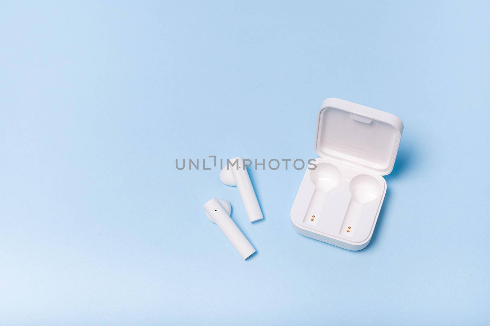 Wireless white headphones on a plain background . White headphones. Solid color background. Modern electronics. Future technology. Wireless music playback. Bluetooth headphones. Article about additional electronics to the phone. Article about choosing headphones.