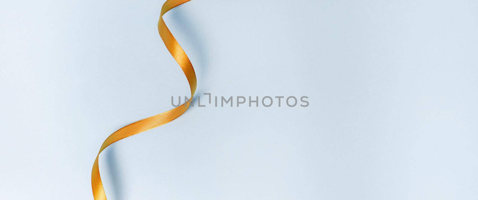 Gold ribbon on a blue background. holiday layout . Decorative ornament. Copy space . The preparation of the article. Blue background