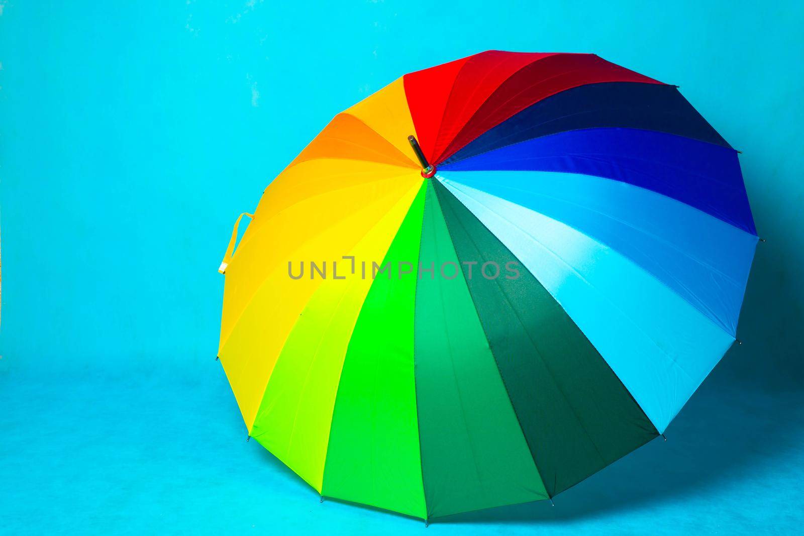Colored umbrella on a blue background . Bright umbrella. Copy space. Article about the protection from the rain.