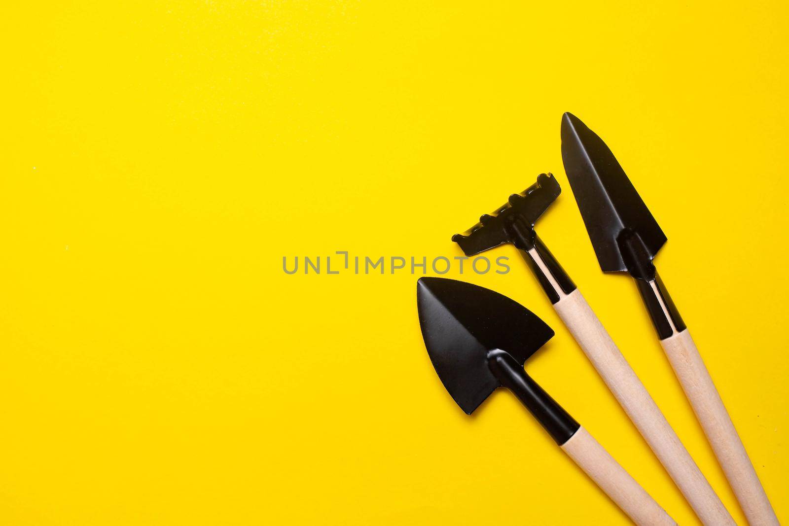 Garden shovels on a yellow background . Gardening layout. Spring planting. The care of plants. Work in the ground. yellow background. Copy space.