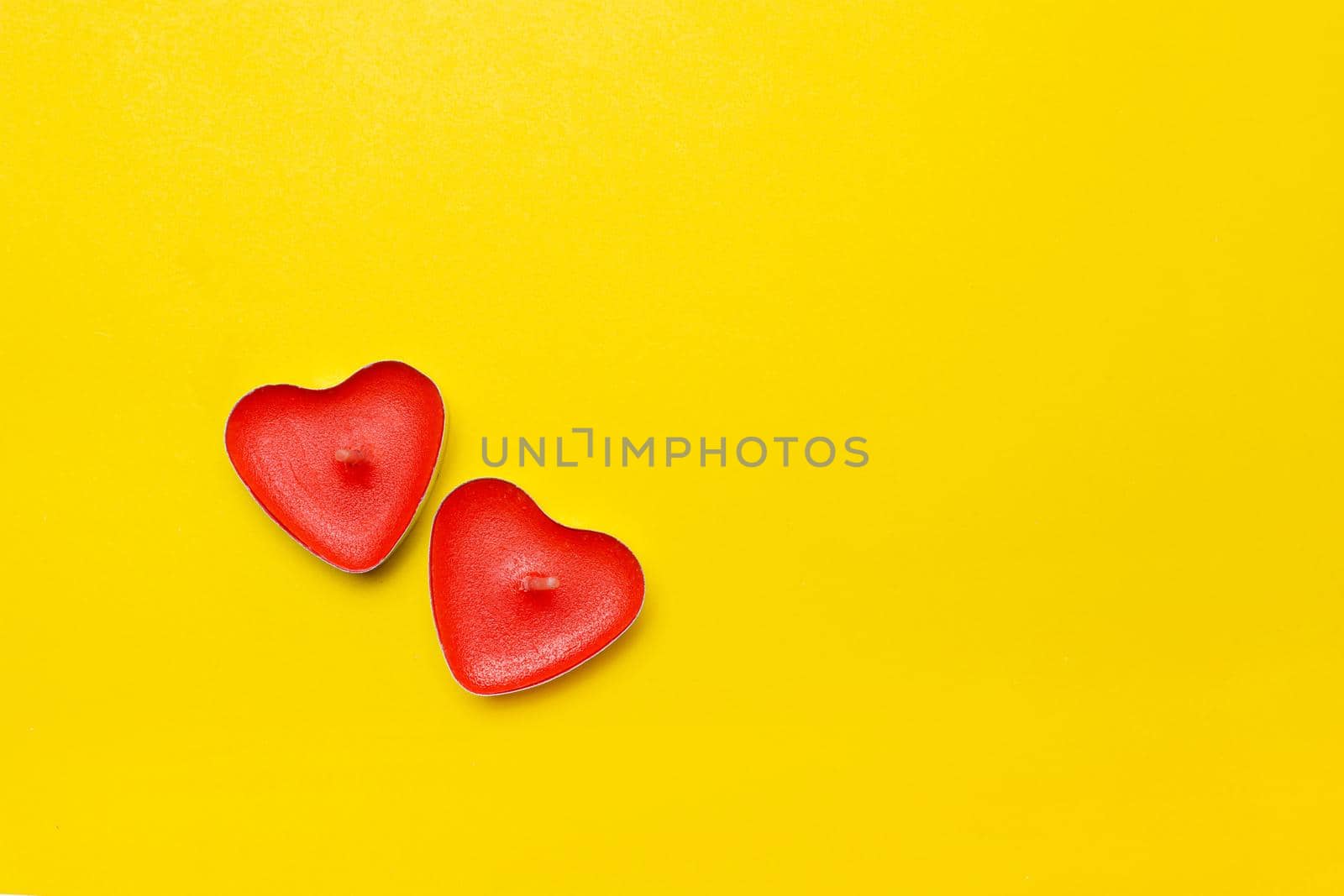 Candles in the form of hearts on a yellow background . Red candles. Red hearts. Yellow background. Copy space. Valentine's Day. Holiday. An article about celebrating Valentine's Day.. An article about love.