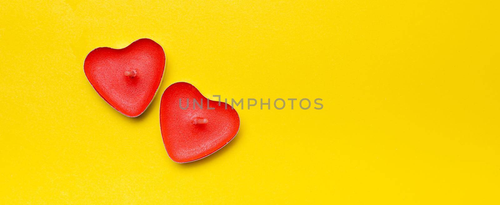 Candles in the form of hearts on a yellow background . Red candles. Red hearts. Yellow background. Copy space. Valentine's Day. Holiday. An article about celebrating Valentine's Day.. An article about love.