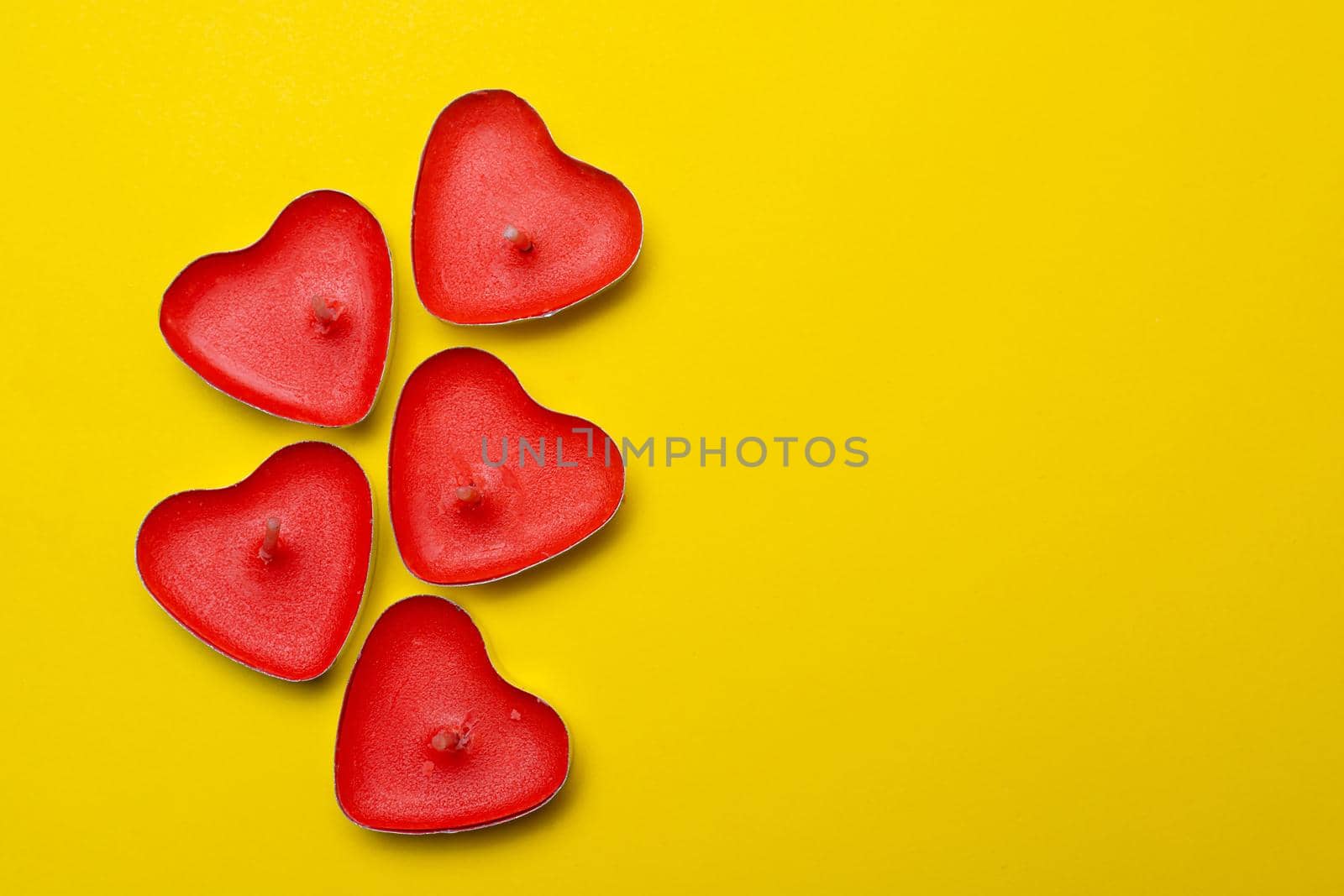 Candles in the form of hearts on a yellow background . Red candles. Red hearts. Yellow background. Copy space. Valentine's Day. Holiday. An article about celebrating Valentine's Day.. An article about love.
