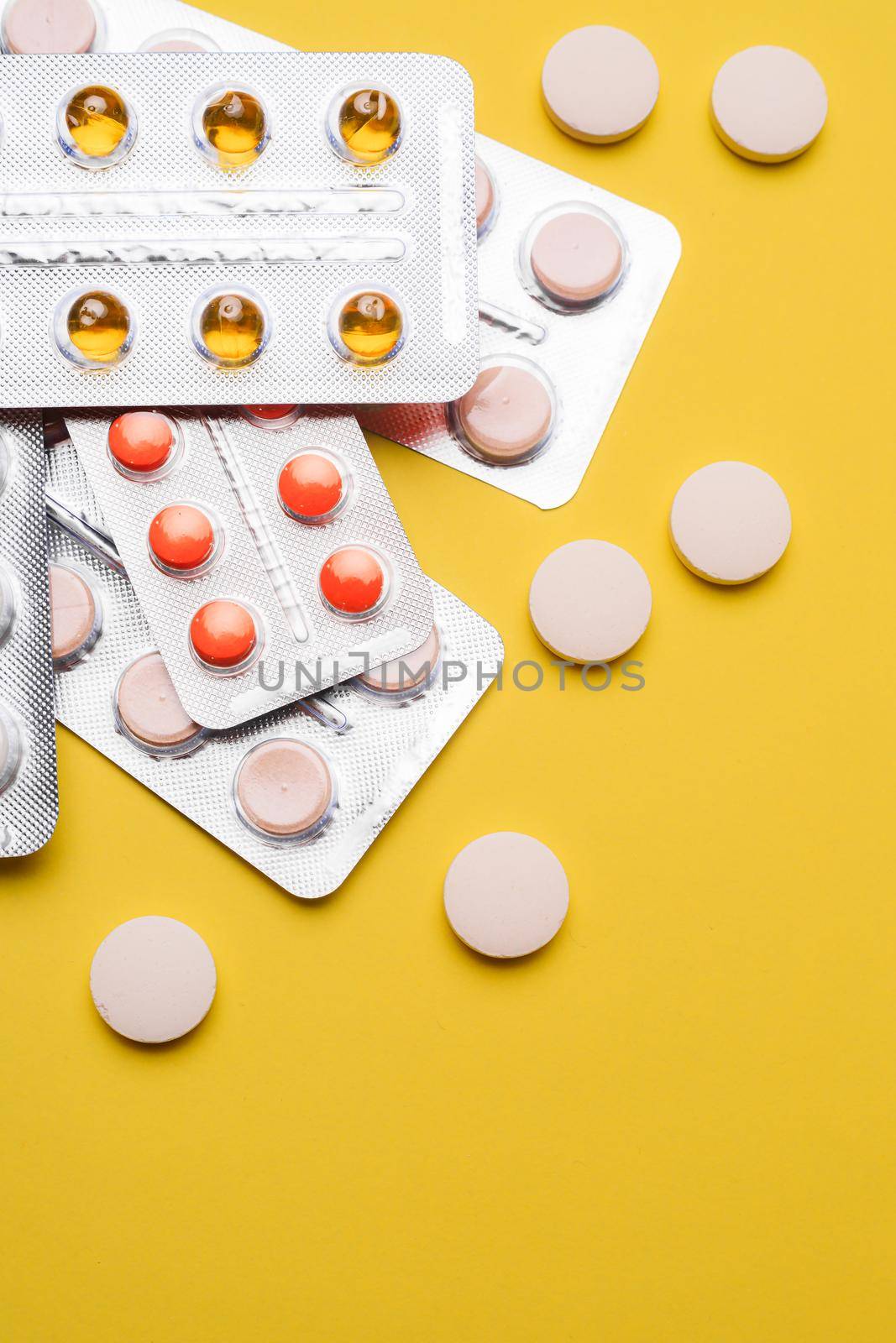 A pile of pills on a yellow background . Treatment and prevention. Article about the purpose of treatment. A cure for the disease. Pills in a blister. Lots of medicine. Yellow background. Copy space