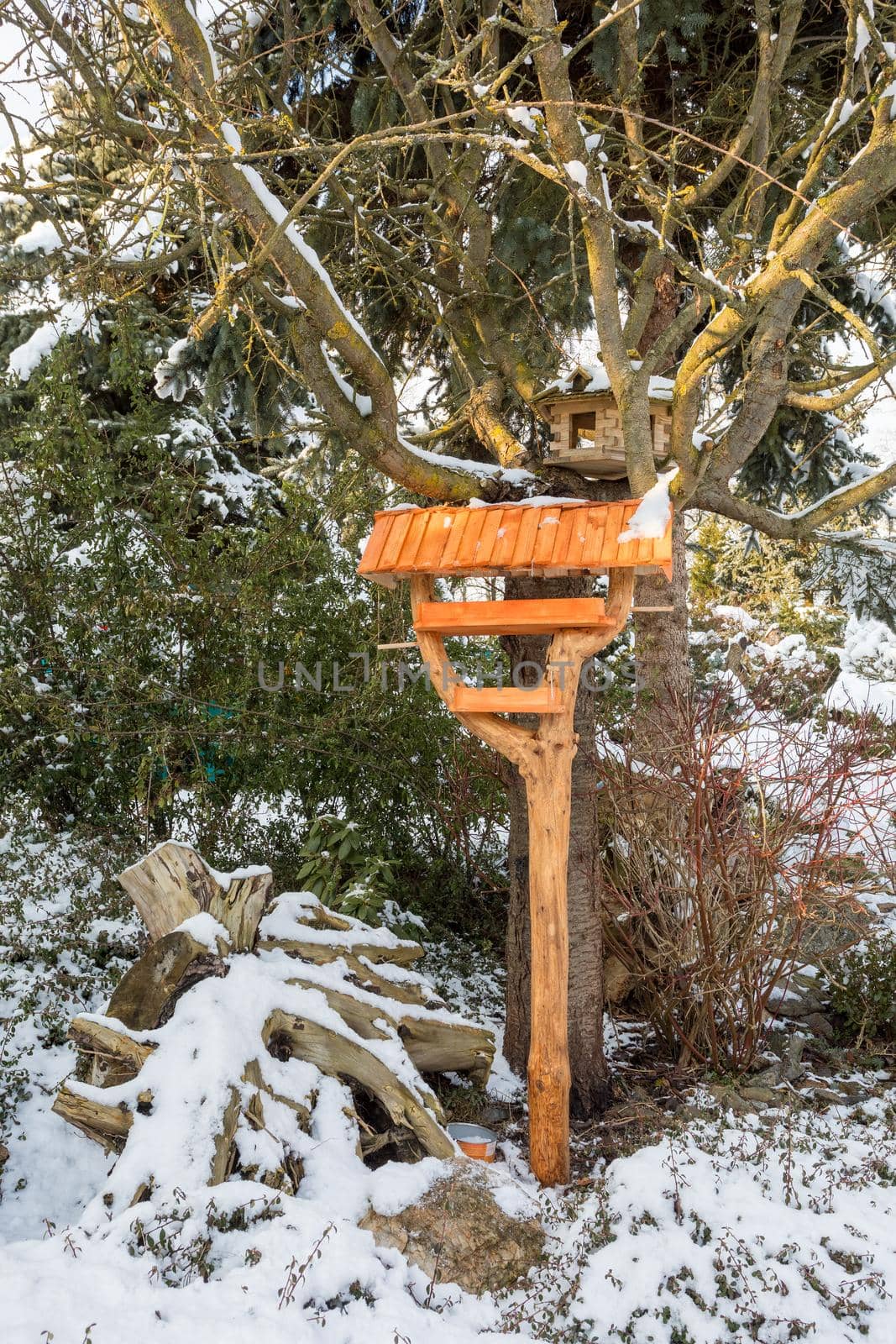 homemade wooden birdhouse or feeder installed on winter garden in snowy day