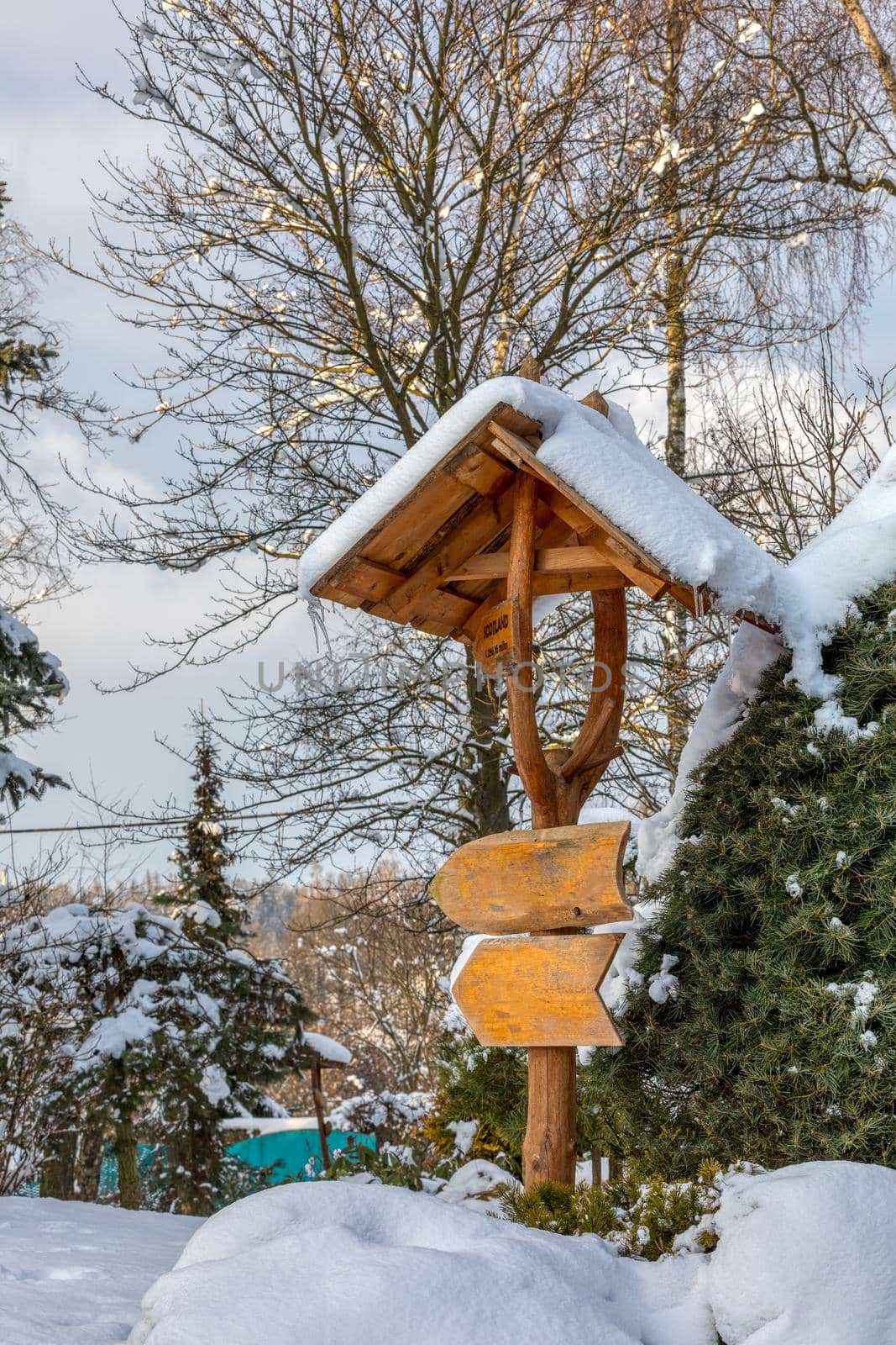 beautiful wooden signpost in winter garden covered with fresh snow