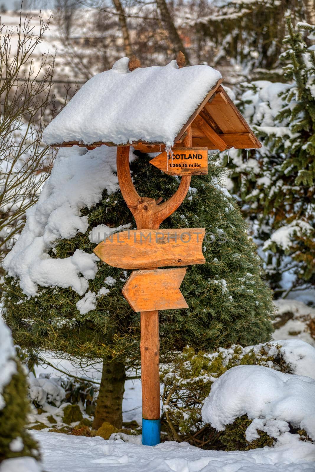 beautiful wooden signpost in winter garden covered with fresh snow