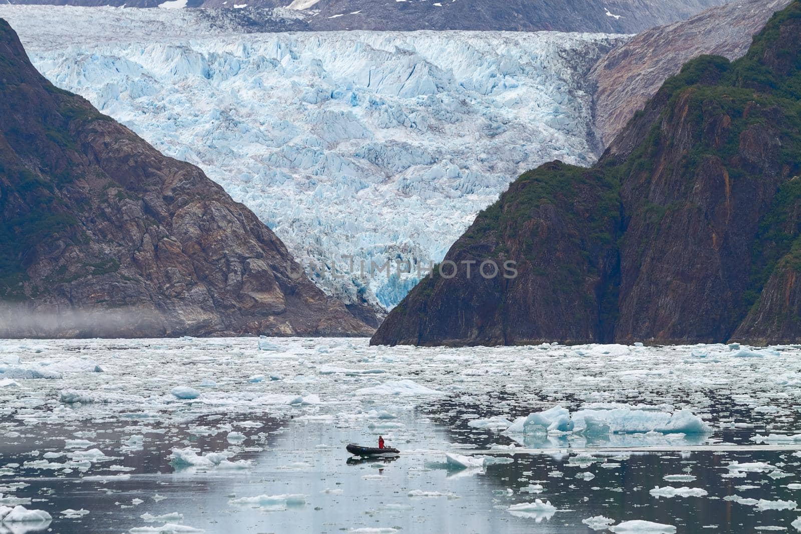 Man in Boat in Front of Sawyer Glacier at Tracy Arms Fjords in Alaska United States.