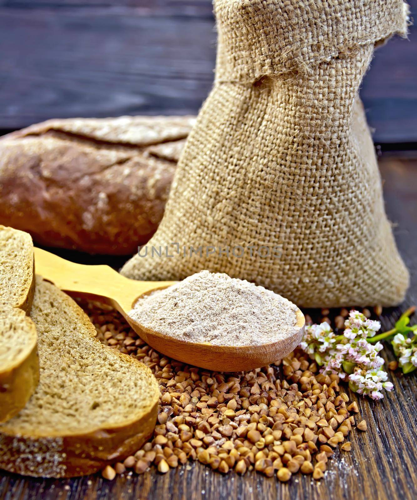 Buckwheat Flour in a wooden spoon, buckwheat in the bag, slices of bread, buckwheat flower on the background of wooden boards