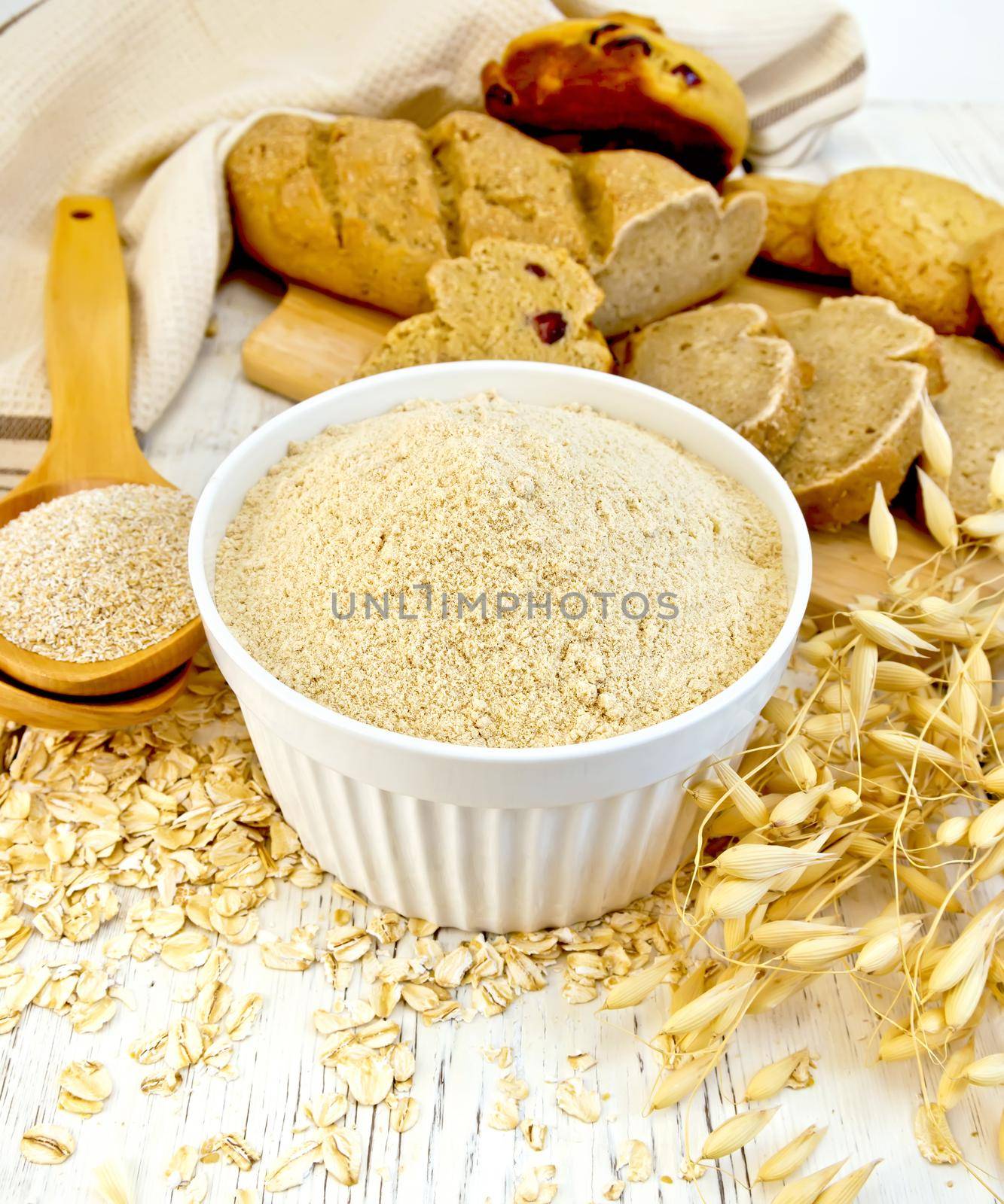 Flour oat in white bowl with bran in spoon on board by rezkrr