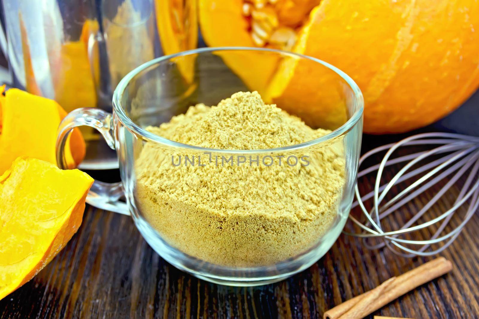 Flour pumpkin in glass cup with sieve and a mixer on board by rezkrr