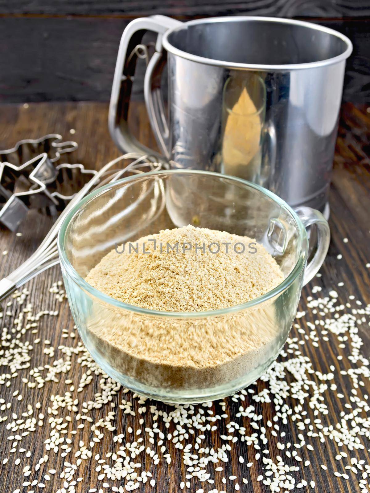 Flour sesame in cup with sieve on dark board by rezkrr