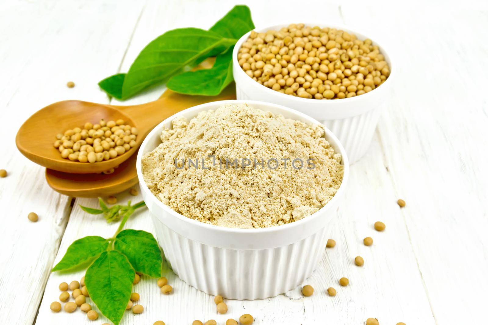 Flour soy with soybeans and leaf on light wooden board by rezkrr