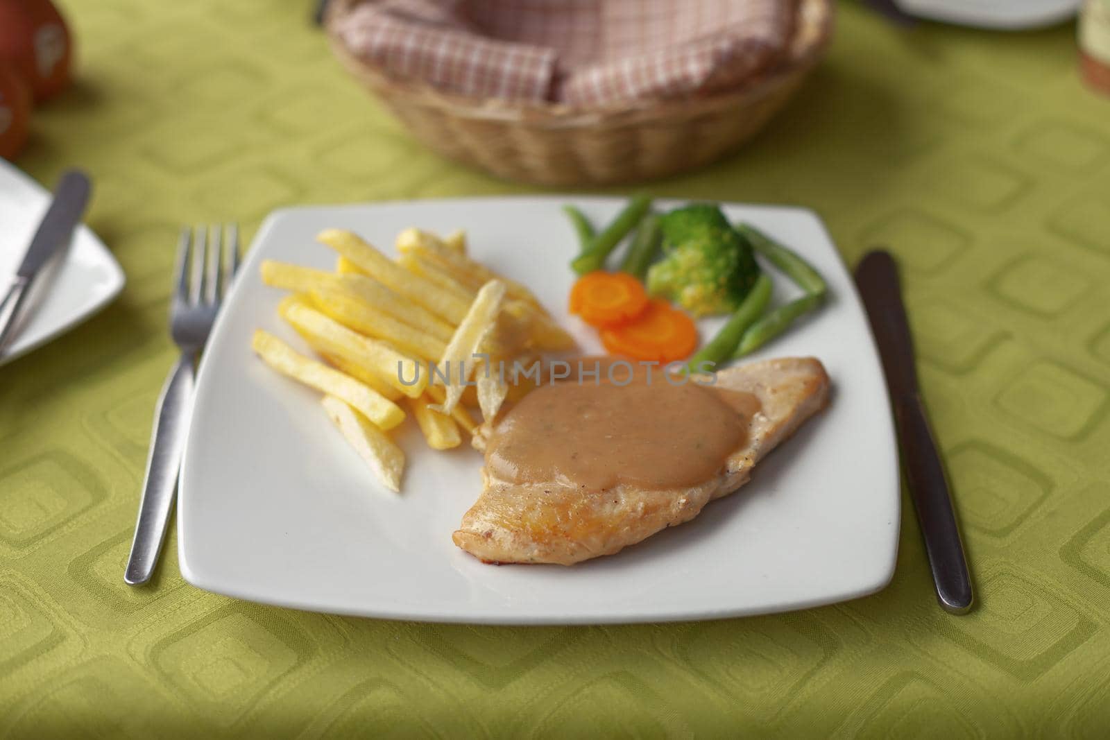 Grilled chicken with colca sauce, french fries and vegetable salad on traditional table setting.