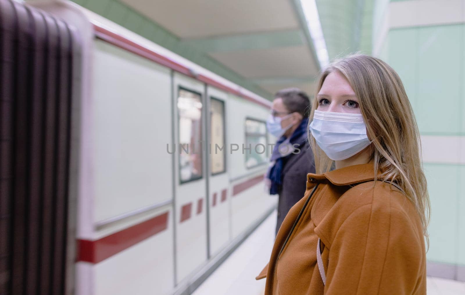 People in public transport wearing mask while train arrives by Kzenon