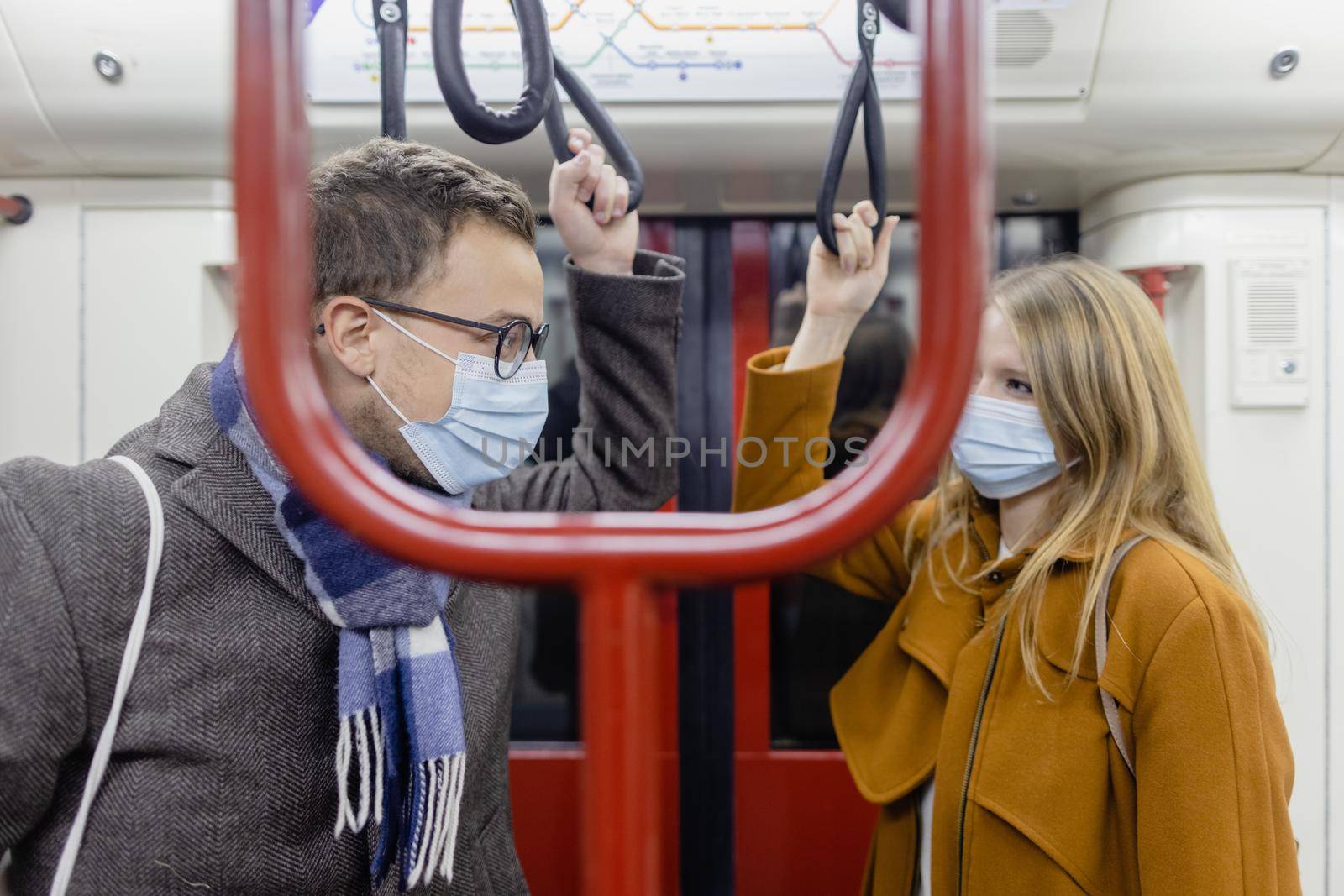 Flirty couple with covid 19 face masks in a train trying to maintain social distance